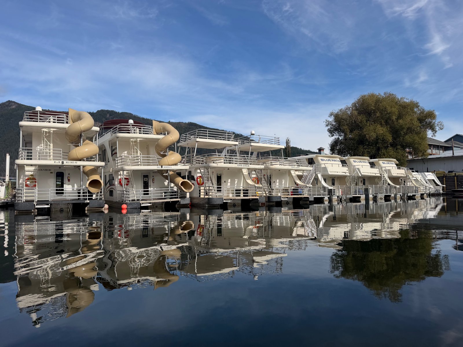 Bluewater houseboats docked at the marina in Sicamous, mirrored in the still water