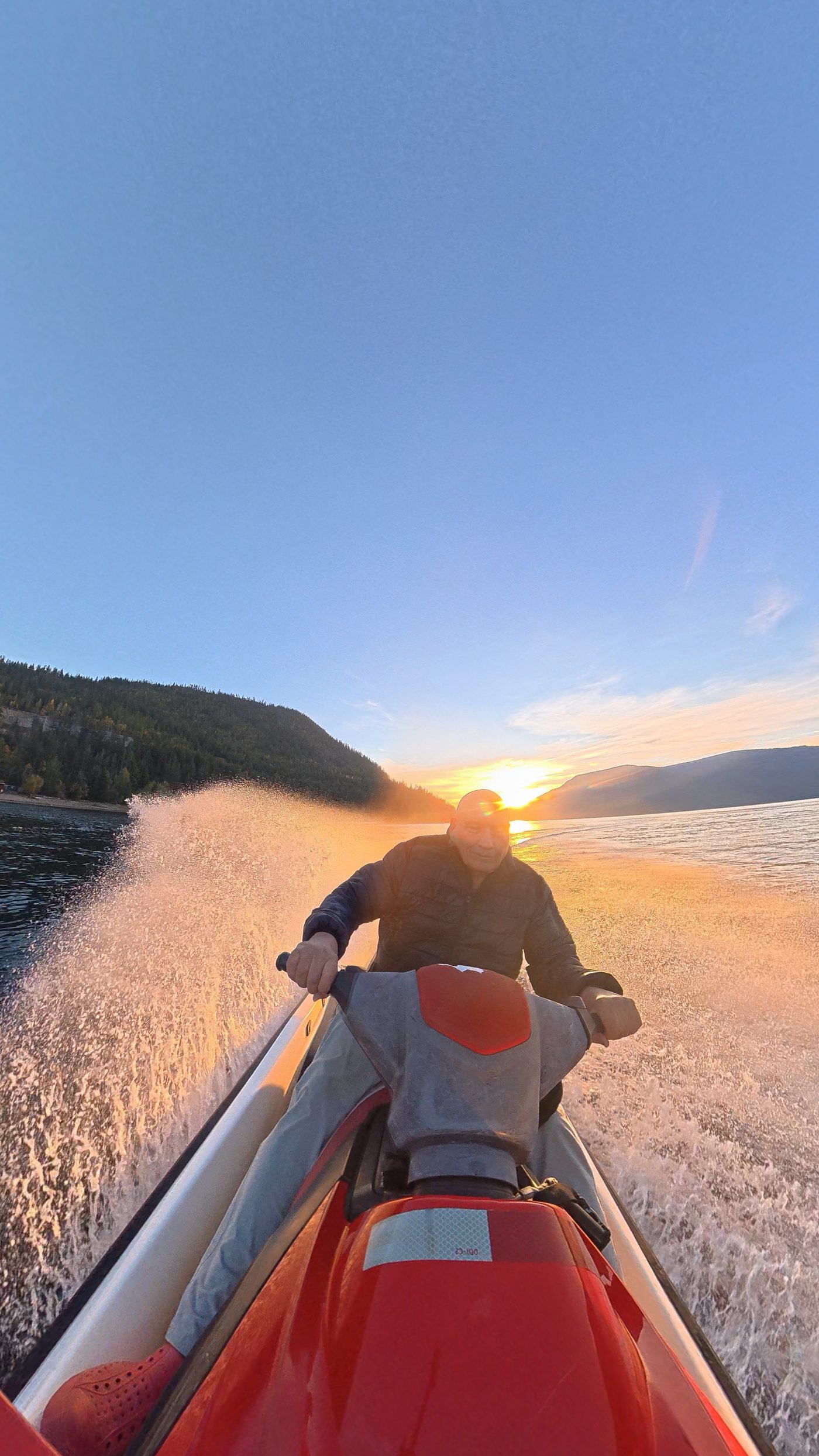 Jet ski on calm Shuswap Lake water under a big evening sky