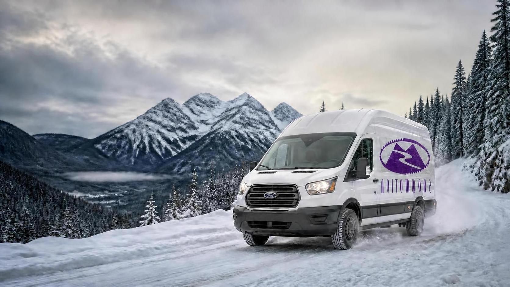 Van below dramatic snow-covered mountain peaks under a moody sky